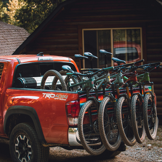 Pickup truck carrying mountain bikes for endurance cycling adventure, representing the need for long-lasting Velovaere chamois cream to stay chafe-free.